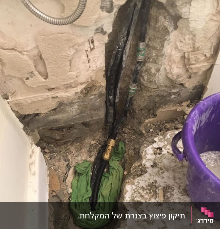 צינורות חשופים בקיר עם דלי סגול